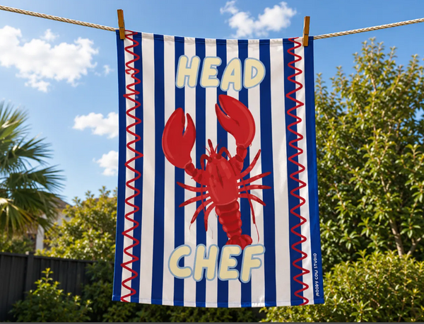 Striped towel with a red lobster graphic and 'Head Chef' text, hanging outdoors.